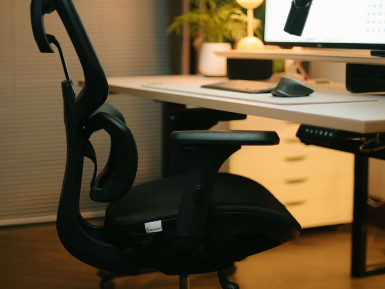 Höhenverstellbarer Schreibtisch mit ergonomischem Bürostuhl, Monitor und Pflanze